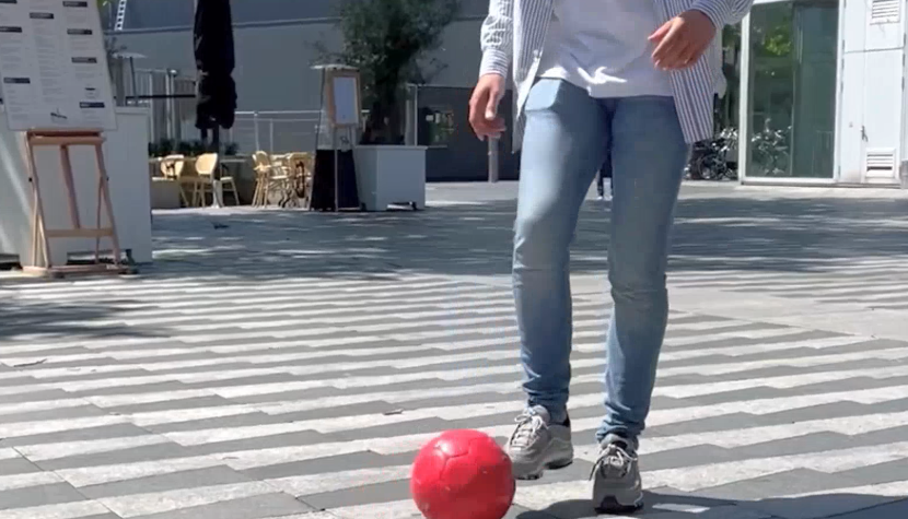 Persoon dribbelt met rode bal op plein